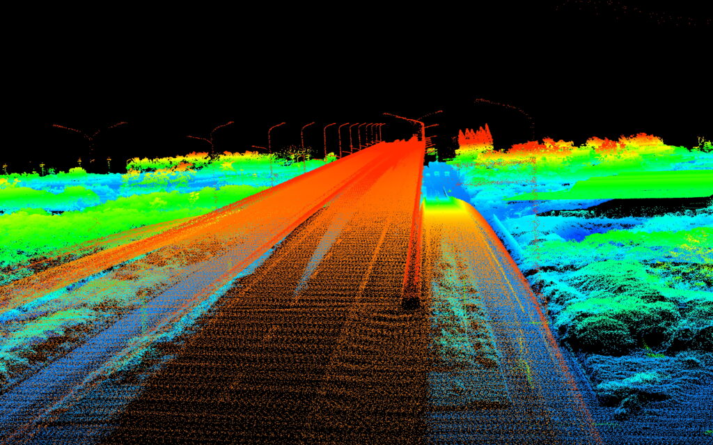 Nuage de points LIDAR haute densité d'un corridor autoroutier, montrant l'élévation de la chaussée, la végétation et les structures environnantes.